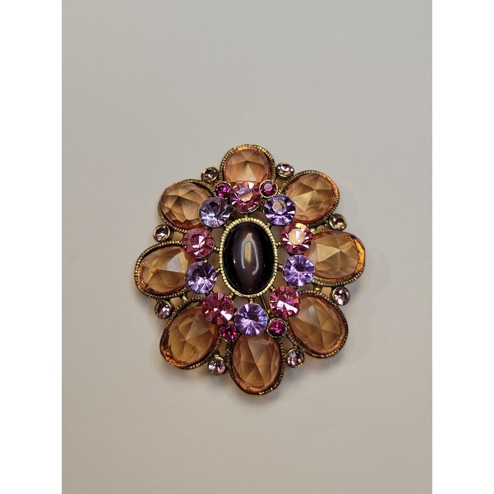 vintage-style costume jewelry brooch featuring a central oval cabochon stone